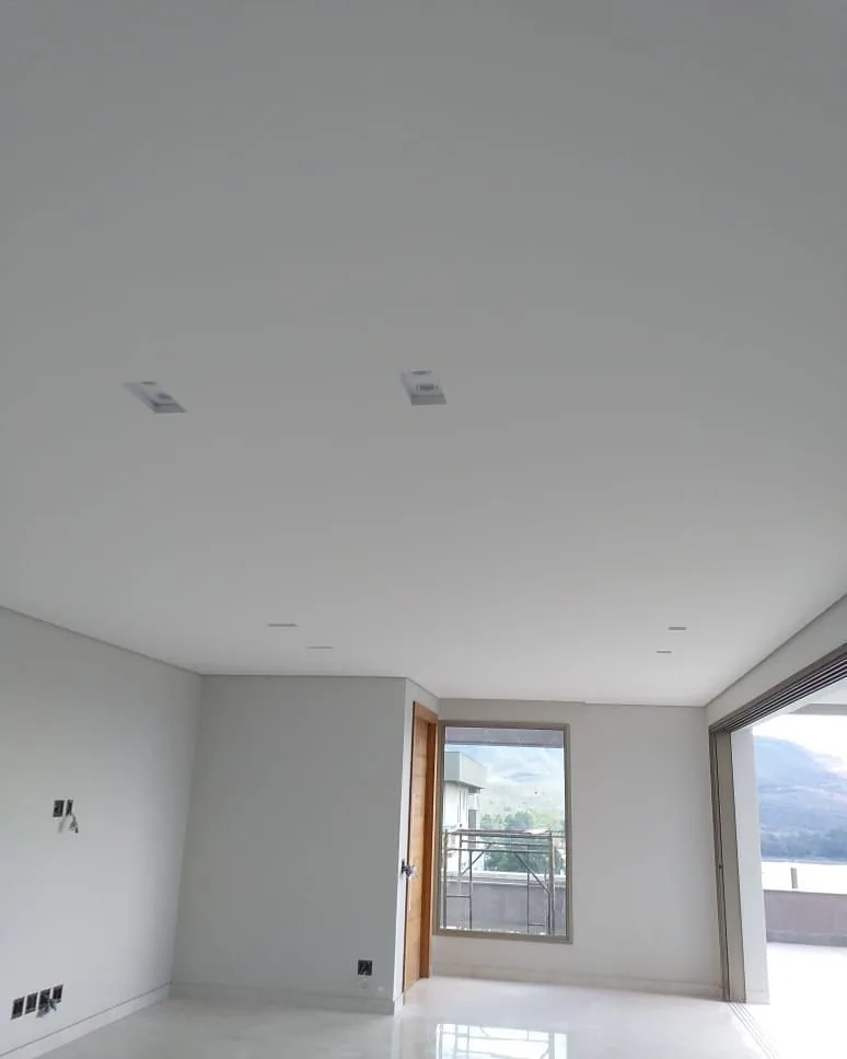 Casa na Península dos Pássaros, em Alphaville: sala vazia com piso claro, porta de vidro para a varanda e forro de gesso liso e branco